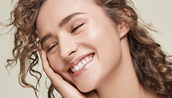 Fotografia asi dvadsaťročnej smejúcej sa ženy svetlej pleti s ryšavými vlasmi a žiariacou pleťou