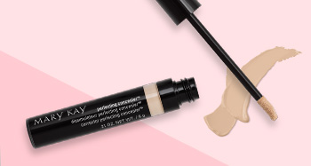 Otvorená tubička korektora Mary Kay Perfecting Concealer vyfotografovaná spoločne s aplikátorom a ukážkou produktu pred pozadím v dvoch odtieňoch ružovej.