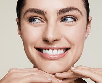 Fotografia usmievajúcej sa dvadsaťročnej ženy so svetlou pleťou a kučeravými vlasmi so zatvorenými očami