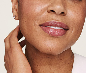 Detail spodnej polovice tváre jemne sa usmievajúcej modelky v zrelom veku 